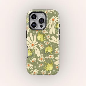 May include: A phone case featuring a repeating pattern of cartoon frogs and daisies. The frogs are yellow-green, and the daisies are white with orange centers. The background is a muted green color.