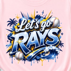 Könnte beinhalten: Ein hellrosa T-Shirt mit einem grafischen Design und dem Schriftzug "Let's go RAYS" in Blau und Weiß. Das Motiv zeigt Basebälle, Palmen und eine Welle in Blau- und Gelbtönen vor einem hellen, farbenfrohen Hintergrund.