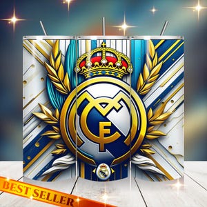 May include: A stainless steel tumbler featuring the Real Madrid logo. The design includes the team's emblem, a crown, and gold accents against a white and blue background. The words "BEST SELLER" are at the bottom.