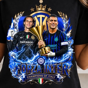 Pode incluir: Camiseta preta com um gráfico de dois jogadores de futebol segurando um troféu, com o texto "FORZA INTER CHAMPIONS OF ITALY". O design inclui raios azuis, uma coroa e o logotipo da equipe. A camisa tem os logotipos "betsson sport" e "etsson sport".