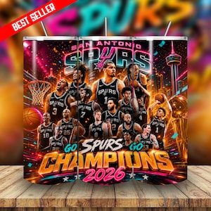 May include: A cylindrical tumbler featuring a San Antonio Spurs basketball theme with multiple players in black jerseys, a basketball hoop, a trophy, and the text "SAN ANTONIO SPURS" and "GO SPURS CHAMPIONS 2026" in bold, vibrant colors.