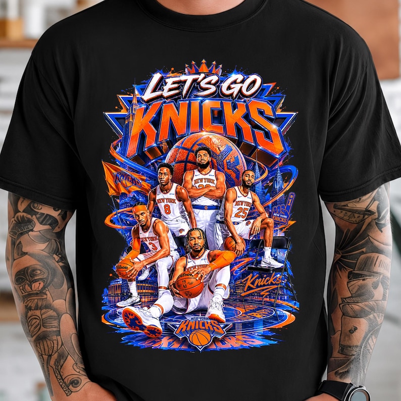 May include: Black t-shirt featuring a graphic of the New York Knicks basketball team. The design includes the words "LET'S GO KNICKS" in orange and blue, along with images of players and a basketball.