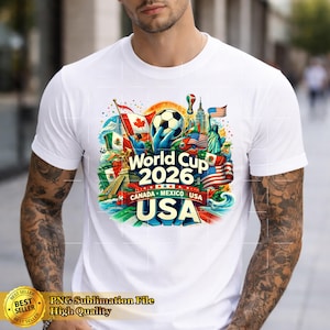 May include: White t-shirt featuring a colorful graphic for the 2026 World Cup, with flags of Canada, Mexico, and the USA. The design includes a soccer ball and the text "World Cup 2026 CANADA MEXICO USA USA".