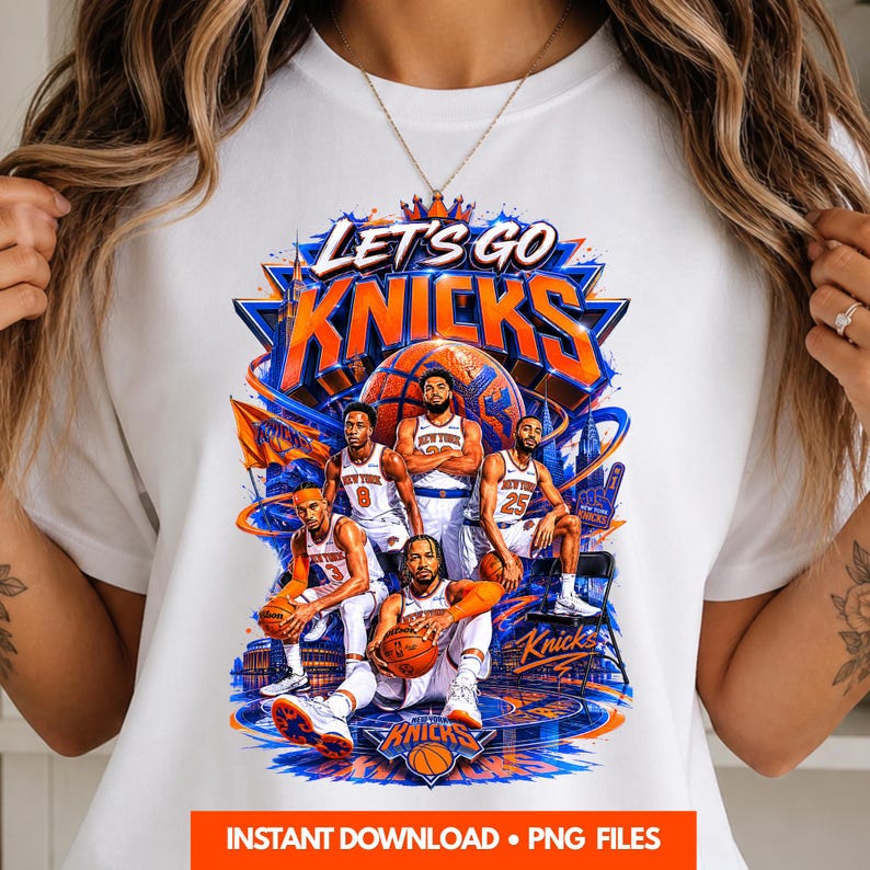 May include: White t-shirt featuring a vibrant graphic of the New York Knicks basketball team. The design includes the words "LET'S GO KNICKS" and images of players, a basketball, and the team's logo in blue and orange.