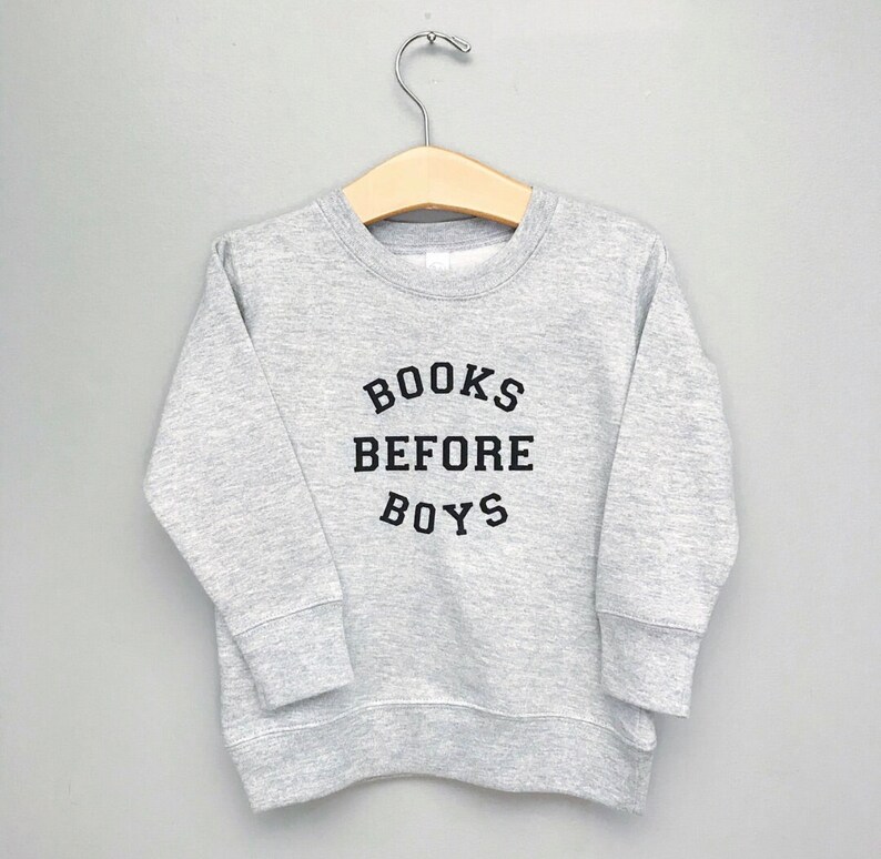 May include: A gray sweatshirt with the text "BOOKS BEFORE BOYS" printed in black.