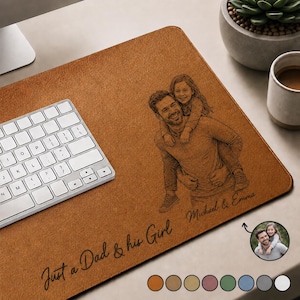 Op de afbeelding: Een bruine rechthoekige bureaumat met een gepersonaliseerde afbeelding van een vader die zijn dochter draagt. De tekst "Just a Dad & his Girl" en de namen "Michael & Emma" staan op de mat. Links staat een wit toetsenbord.