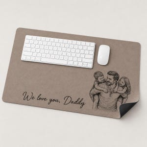 May include: A rectangular desk mat in a neutral brown hue, with a white keyboard and mouse. A pencil sketch of a father with two children is on the right. The text "We love you, Daddy" is printed in black.