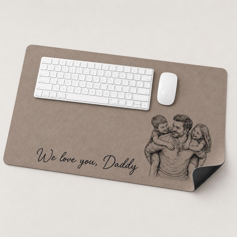 May include: A rectangular desk mat in a neutral brown hue, with a white keyboard and mouse. A pencil sketch of a father with two children is on the right. The text "We love you, Daddy" is printed in black.