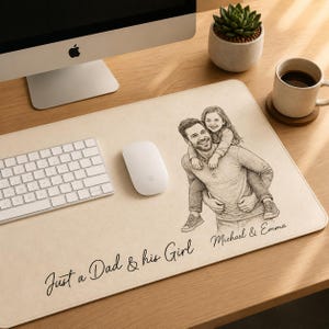 May include: A beige rectangular desk mat with a pencil sketch of a father carrying his daughter. The text "Just a Dad & his Girl" and names "Michael & Emma" are printed on the mat. A computer, keyboard, and mouse are on the desk.