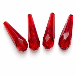 May include: Four translucent red teardrop-shaped beads with a faceted surface. Each bead features a pointed top and a wider, rounded base with a small hole for stringing. The vibrant red material catches the light, highlighting the geometric facets.