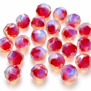 May include: A collection of twenty-one round, faceted beads with a vibrant red core and an iridescent, opalescent finish. Each bead features multiple geometric facets that catch the light, creating a shimmering effect across the surface.