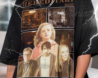 May include: Black t-shirt featuring a collage of images from the movie "Hereditary." The design includes the film's title, cast names, and various scenes. The shirt has a crew neck and short sleeves.