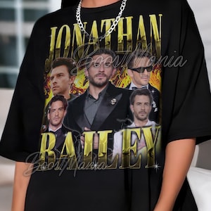 May include: Black t-shirt featuring a gold-colored graphic of Jonathan Bailey with the name in large gold letters. The shirt has a crew neck and short sleeves. The text "Boost Mania" is also visible.