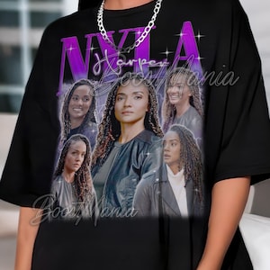 May include: Black t-shirt featuring a graphic of a woman with multiple images of her face. The design includes the name "NYLA Harper" in purple, with the text "Boos Mania" in a script font at the bottom.