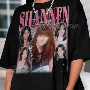 Könnte beinhalten: Schwarzes T-Shirt mit einer Collage von Shannen Doherty-Bildern und dem Text "Shannen Doherty Boos Mania" in Rosa und Weiß. Das Design hat eine Retro- und Vintage-Ästhetik.