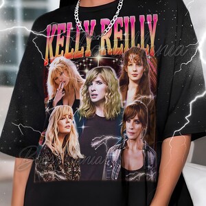 Könnte beinhalten: Schwarzes T-Shirt mit einer Grafik von Kelly Reilly und dem Text "KELLY REILLY" in Pink und Gelb. Das Shirt hat ein Design im Vintage-Stil mit mehreren Bildern der Schauspielerin. Eine silberne Kette wird getragen.