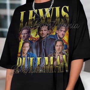 Puede incluir: Camiseta negra con un gráfico dorado de Lewis Pullman y el texto "LEWIS PULLMAN". El diseño incluye múltiples imágenes del actor. La camiseta tiene cuello redondo y mangas cortas.