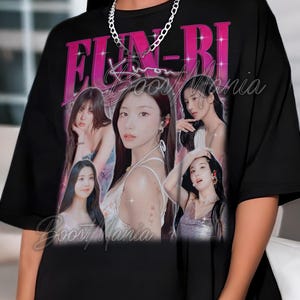 May include: Black t-shirt featuring a graphic design with the text "FUN-BI" in pink and a collage of women's portraits. The words "Boost Mania" are also visible on the shirt. A silver chain necklace is worn.