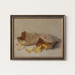 May include: A framed painting depicts two open paper bags of potato chips, with chips spilling out onto a white surface. The bags are brown and white, and the chips are golden yellow. The frame is black with a gold inner edge.