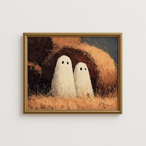 May include: A framed painting shows two white ghost figures with black eyes, set within a hay bale. The artwork uses a warm palette of browns, oranges, and blues, creating a cosy, autumnal scene. The painting is framed in a gold-coloured frame.