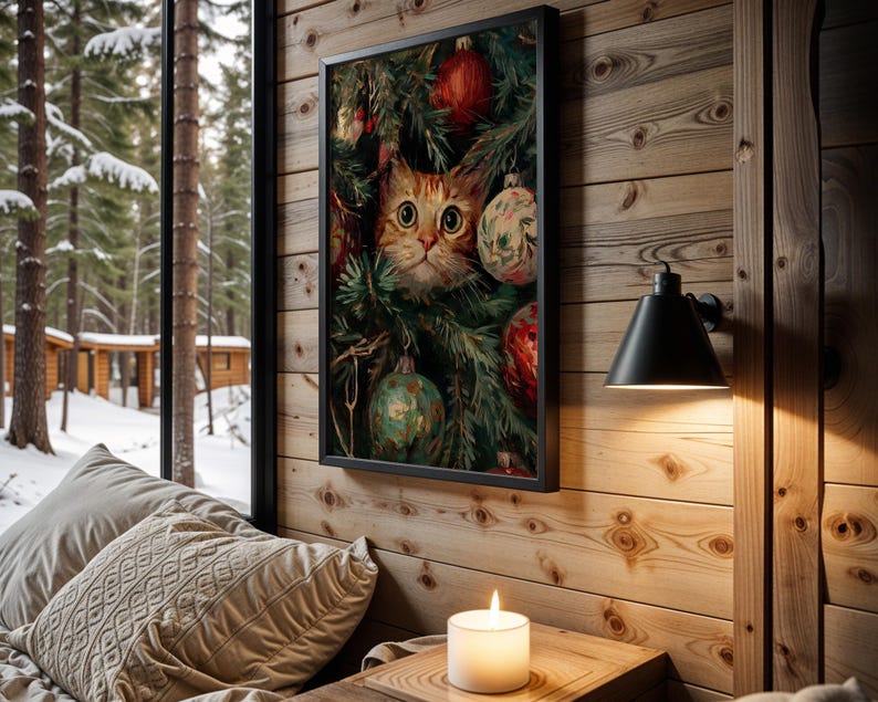 May include: A framed print featuring a cat peering through Christmas tree branches adorned with ornaments. The cat has orange and white fur and large, expressive eyes. The print is displayed on a wooden wall, with a lit candle and a window overlooking a snowy forest.