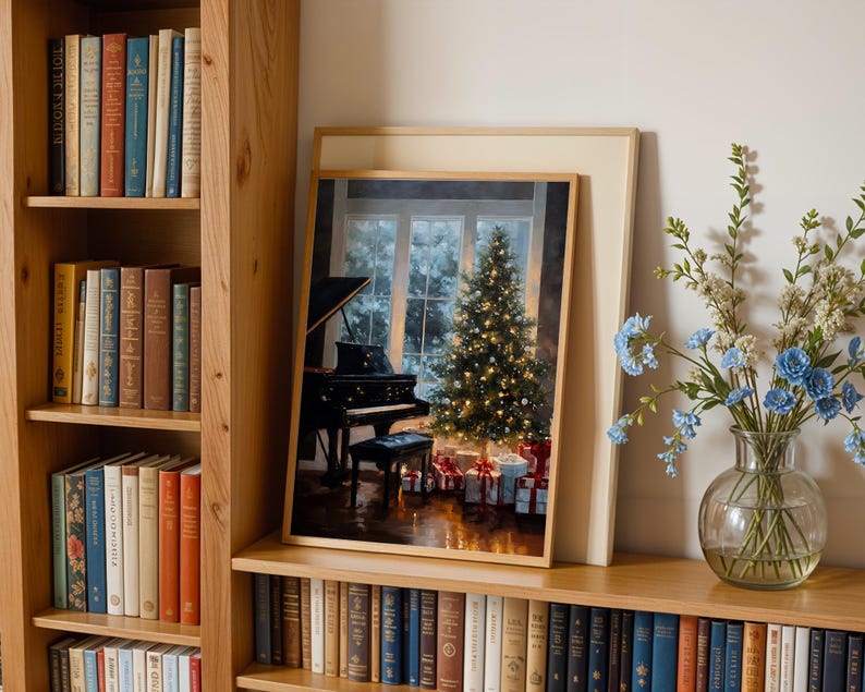 May include: A framed print depicts a Christmas scene with a decorated tree, gifts, and a grand piano. The print is displayed on a wooden shelf with a vase of blue flowers. Bookshelves filled with books are on either side.
