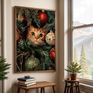 May include: A framed print featuring a ginger cat peeking through a Christmas tree. The cat has large, round eyes and is surrounded by green pine needles and colorful ornaments. The artwork is displayed on a wall near a window with a mountain view.