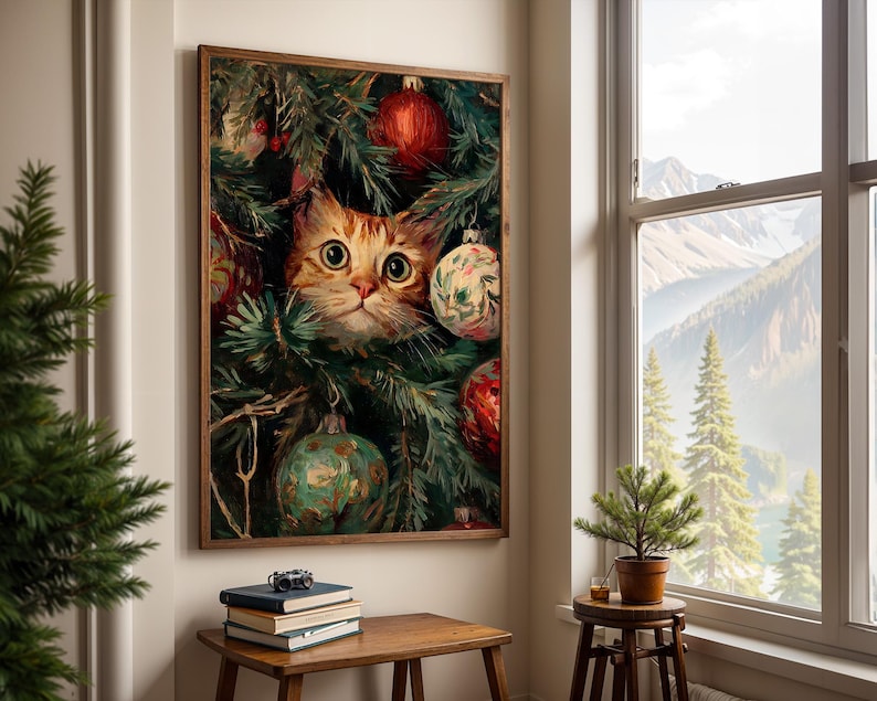 May include: A framed print featuring a ginger cat peeking through a Christmas tree. The cat has large, round eyes and is surrounded by green pine needles and colorful ornaments. The artwork is displayed on a wall near a window with a mountain view.