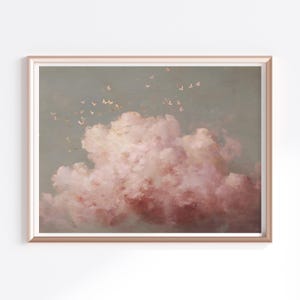 Puede incluir: Impresión enmarcada que presenta una pintura de paisaje de nubes de estilo vintage. La obra de arte muestra una gran nube esponjosa en tonos rosas y rojos sobre un fondo gris verdoso apagado. Pequeñas formas claras, posiblemente mariposas, están dispersas sobre la nube.