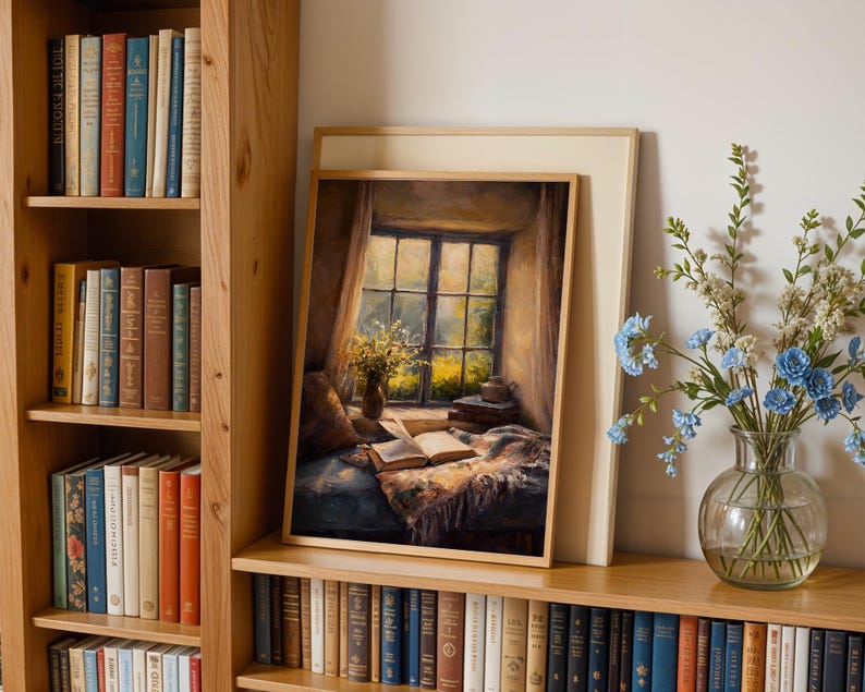 May include: A framed painting depicts a cozy reading nook with an open book, a window, and a vase of flowers. The painting is set on a wooden shelf, surrounded by bookshelves filled with books. A glass vase with blue flowers sits nearby.