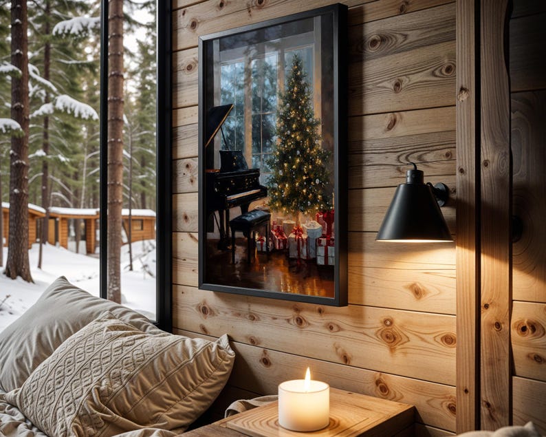 May include: A framed print depicts a Christmas scene with a piano, decorated tree, and wrapped gifts. The print hangs on a wood-paneled wall next to a black sconce. A lit candle sits on a wooden table near a window overlooking a snowy forest.