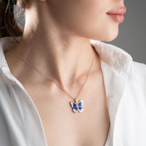 May include: A delicate gold chain necklace with a blue and white enamel butterfly pendant.