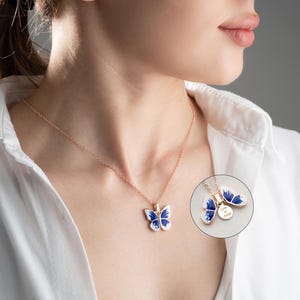May include: A delicate gold chain necklace with a blue and white enamel butterfly pendant. The butterfly has a detailed design and is a beautiful piece of jewellery.
