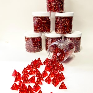 May include: A stack of six clear plastic jars filled with red four-sided dice. The jars have white lids. One jar is tipped over, spilling the dice onto a white surface.