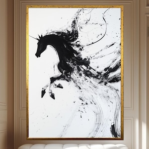 Könnte beinhalten: Abstrakte Schwarz-Weiß-Malerei eines Einhorns mit goldenem Rahmen. Das Kunstwerk zeigt ein sich aufbäumendes Einhorn mit fließender Mähne und Schweif, geschaffen mit kräftigen Pinselstrichen. Der Hintergrund ist weiß und der Rahmen ist goldfarben.