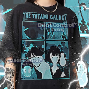 以下が含まれることがあります： 黒色のユニセックスTシャツ。アニメ「The Tatami Galaxy」のティール色のグラフィックが特徴。デザインにはタイトル、キャラクターイラスト、そして「Dual Control On Etsy」の文字が含まれています。Tシャツのテキストは「A Film by Masaaki Yuasa」です。