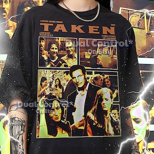 Puede incluir: Camiseta negra con un collage de imágenes de la película Taken. Las imágenes incluyen a Liam Neeson, Maggie Grace, Famke Janssen y Leland Orser. El texto "Taken" está impreso en letras grandes y en negrita en la parte superior de la camiseta. El texto "A film by Pierre Morel" está impreso debajo del título. El texto "2008" está impreso en la esquina superior derecha de la camiseta.