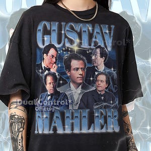 Puede incluir: Camiseta unisex negra con un retrato de Gustav Mahler y el texto "GUSTAV MAHLER" en azul, con un estilo vintage. La camiseta incluye múltiples imágenes del compositor. El texto en la parte inferior indica que la camiseta es fiel a la talla.