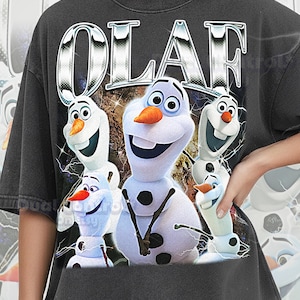 May include: Dark grey Comfort Colors t-shirt featuring a graphic of Olaf from Frozen. The word "OLAF" is displayed above the character in a silver, metallic font. The shirt has a vintage, distressed look.
