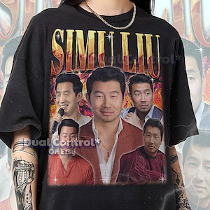 以下が含まれることがあります： 黒色のユニセックスTシャツ。人物の画像をコラージュし、金色の文字で「SIMU LIU」と書かれています。シャツには「Dual Control On Etsy」の文字とサイズ情報が含まれています。