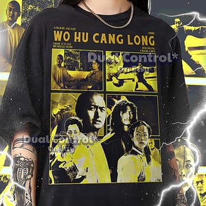 Może przedstawiać: Czarny T-shirt z żółtym nadrukiem graficznym filmu "Przyczajony Tygrys, Ukryty Smok" przedstawiającym tytuł, nazwiska aktorów i sceny z filmu. Tekst na koszulce brzmi "Film Anga Lee, Wo Hu Cang Long, 2000, Chow Yun Fat, Michelle Yeoh, Ziyi Zhang, Chang Chen".