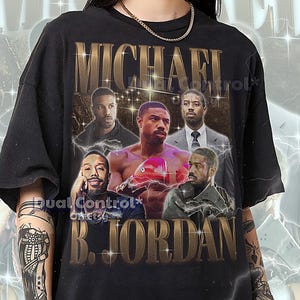May include: Black unisex t-shirt featuring a collage of Michael B. Jordan images with the text "MICHAEL B. JORDAN" in gold lettering. The shirt has a vintage aesthetic and is made of a soft material.