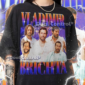 May include: Black unisex t-shirt featuring a graphic of a group of men with the text "VLADIMIR BRICHTA" in a gradient font. The shirt has the Etsy shop name "Dual Control" printed on it. The shirt is a 2XL size.