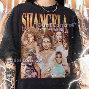 May include: Black unisex t-shirt featuring a graphic of Shangela with the text "SHANGELA" in gold. The shirt includes the text "Dual Control* On Etsy" and a sizing guide.