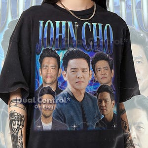 May include: Black unisex t-shirt featuring a graphic of John Cho with the text "JOHN CHO" in blue. The shirt includes multiple images of the actor. The text "Dual Control* Oh Etsy" is also visible.