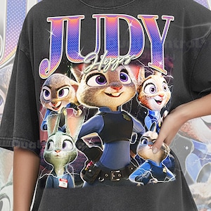 Puede incluir: Camiseta gris oscuro con un gráfico de Judy Hopps de Zootopia. El diseño incluye el nombre "JUDY" en una fuente retro, con Judy y otros personajes con uniformes de policía. La camiseta tiene las palabras "COMFORT COLOR PEPPER" en la parte inferior.