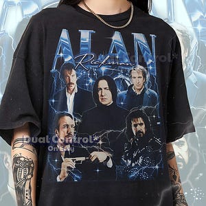 May include: Black unisex t-shirt featuring a graphic of Alan Rickman and other actors. The design includes the name "ALAN" in a stylized font with lightning bolt accents. The shirt is a vintage style.