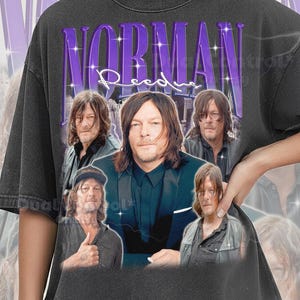 May include: Dark grey Comfort Colors Pepper t-shirt with a purple graphic featuring the name "NORMAN REEDUS" and multiple images of the actor. The shirt has a vintage, distressed appearance.