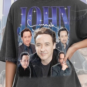 May include: Dark grey Comfort Colors t-shirt featuring a collage of images of John Cusack. The word "JOHN" is in large, blue, stylized text above the images, with "Cusack" in a cursive font. The shirt has a vintage look.