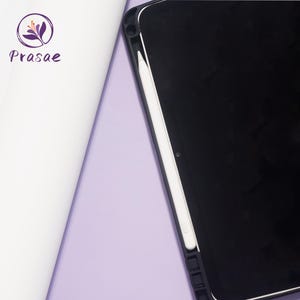May include: A black tablet with a white stylus in a black case, set against a light purple background. A white roll of paper and the logo "Prasae" are in the upper left corner.